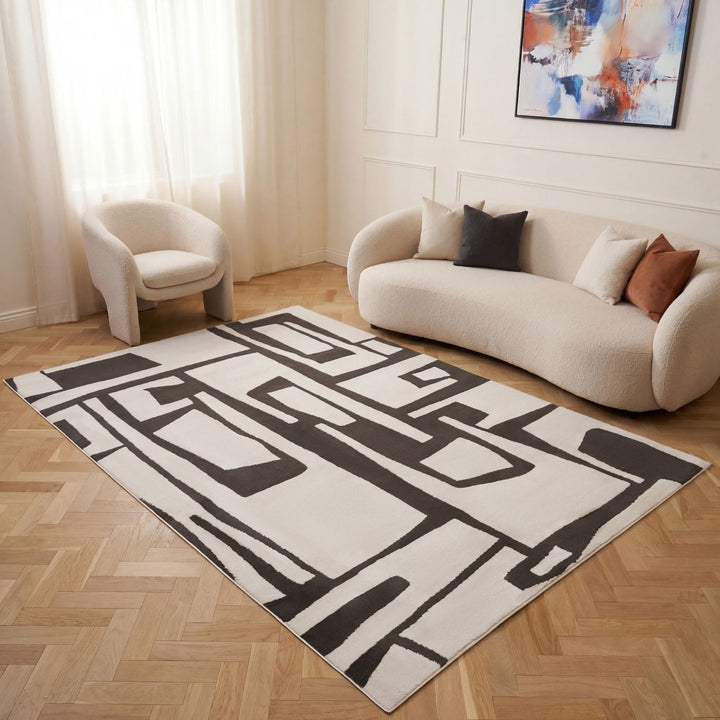 Modern living room with a geometric patterned rug, sofa, and abstract painting.