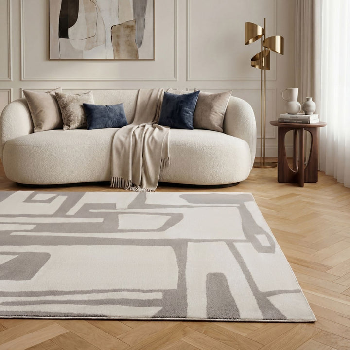 Modern living room with a beige sofa, abstract rug, and decorative elements.
