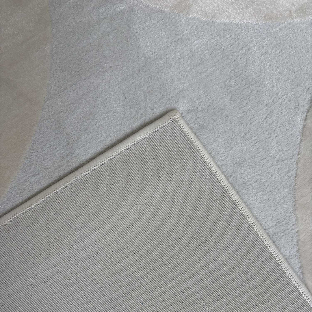 Close-up of a light gray rug with a textured border on a neutral background