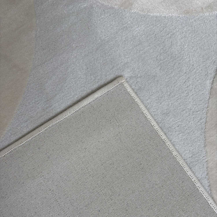 Close-up of a light gray rug with a textured border on a neutral background