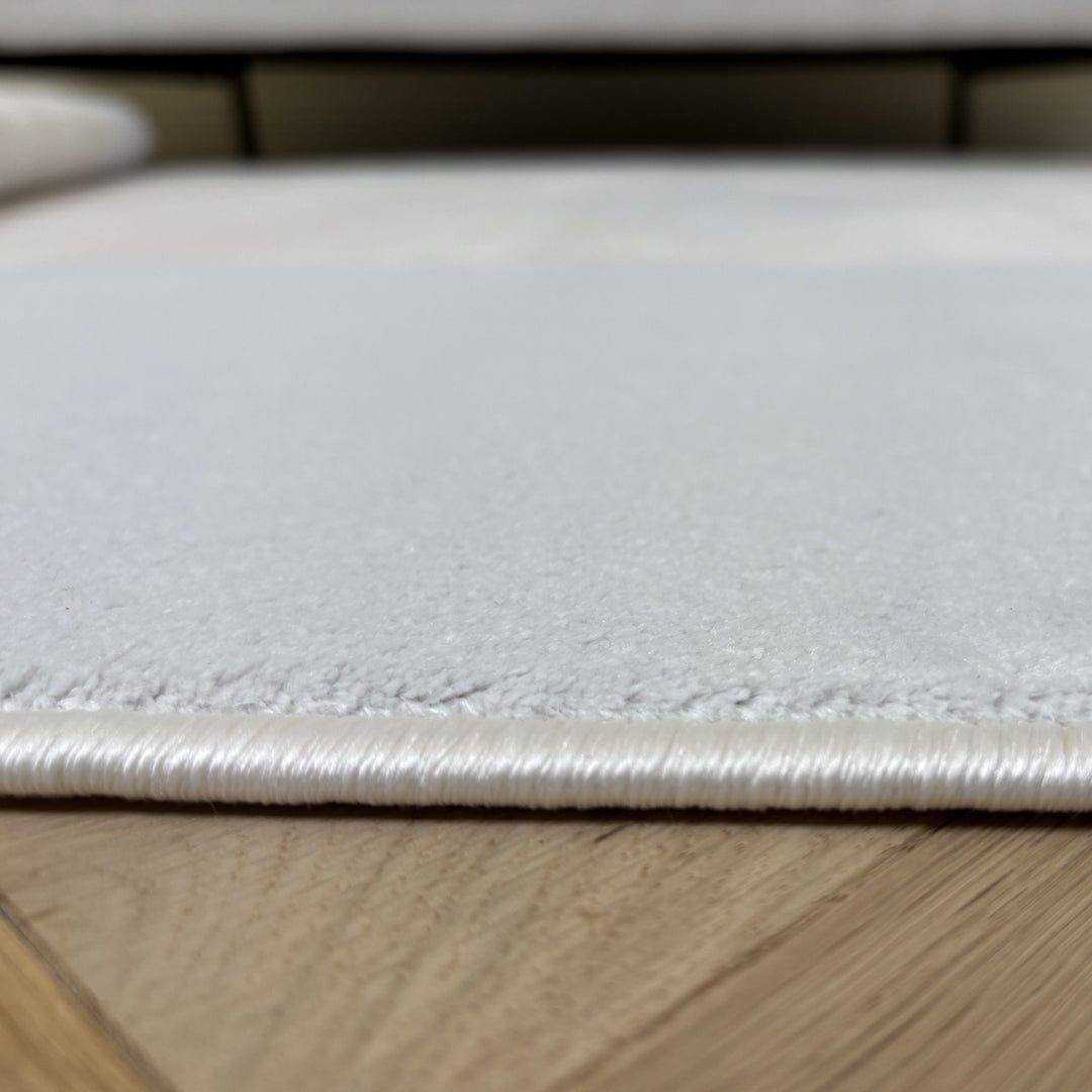 Close-up of a white leather surface with stitching on a wooden floor.