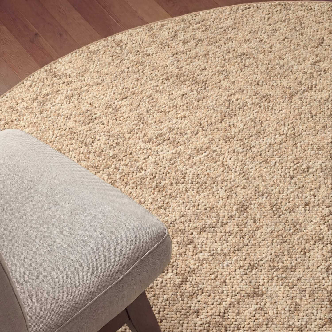 Beige textured rug with a gray cushion on a wooden floor