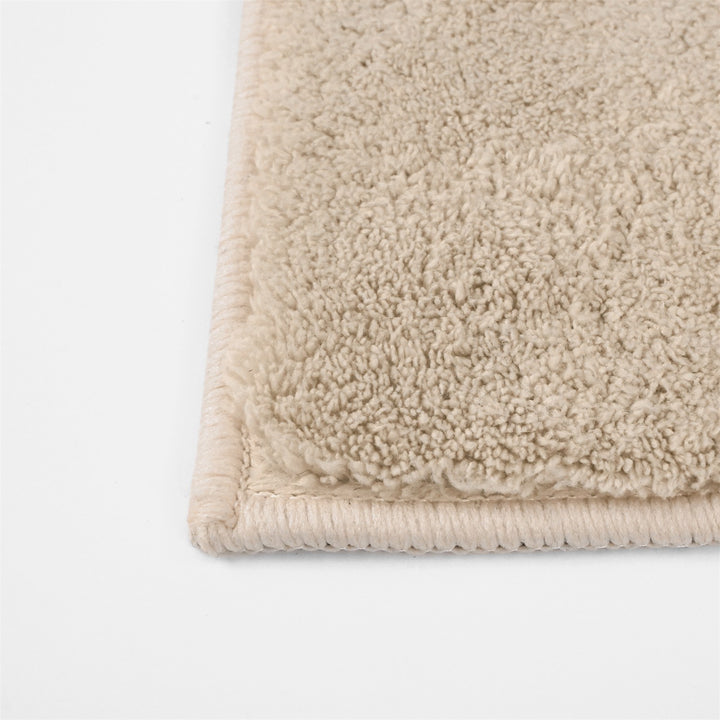 Washmellow beige washable rug, close-up of the corner and bound edge | The Rugs