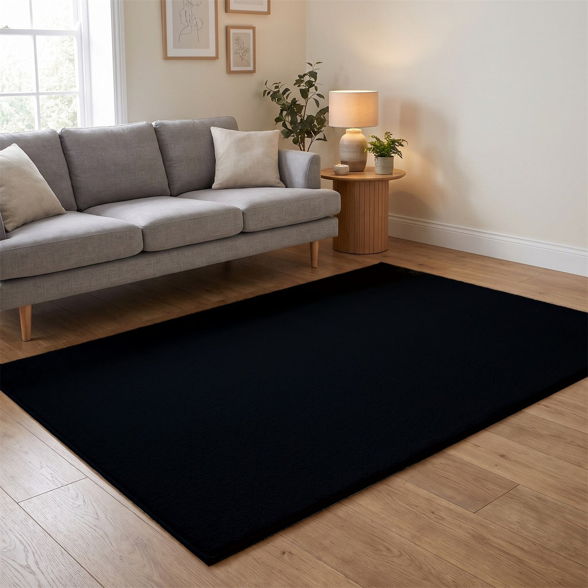 Washmellow black washable rug in a living room with a grey sofa and oak floor | The Rugs