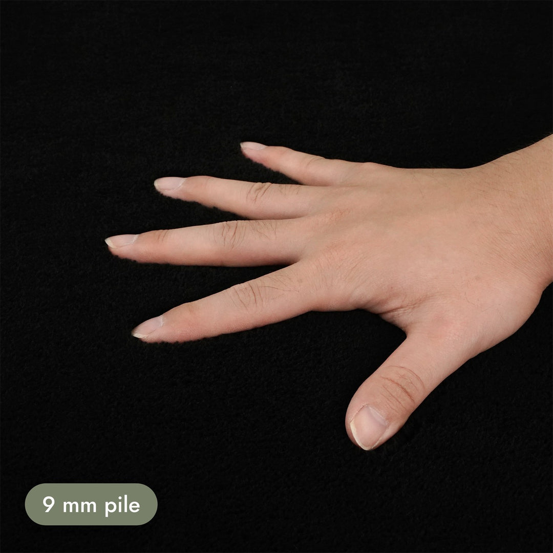 Washmellow black washable rug, close-up of the soft 9mm pile under a hand | The Rugs