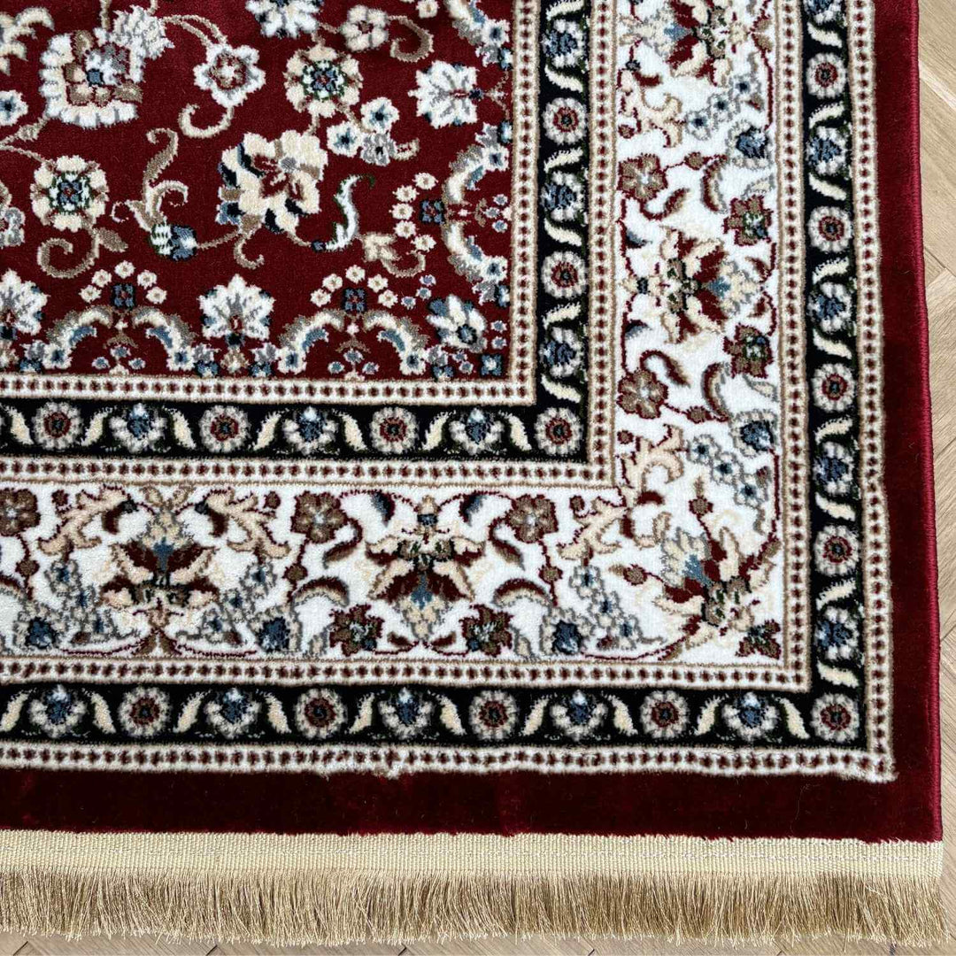 Close-up of a patterned rug with floral designs on a wooden floor.