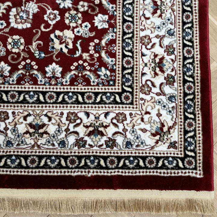 Close-up of a patterned rug with floral designs on a wooden floor.
