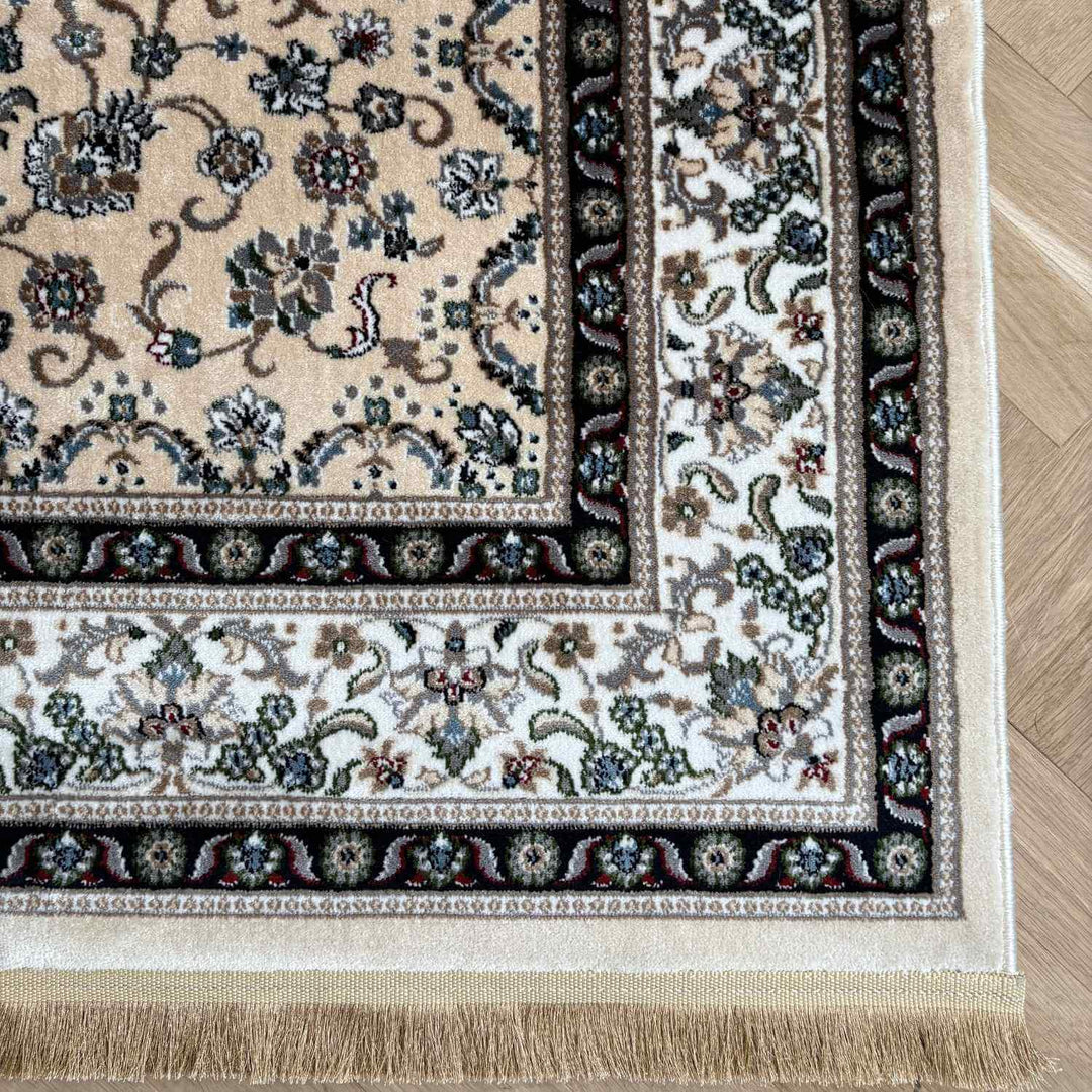 Corner of a patterned rug with intricate designs on a wooden floor.