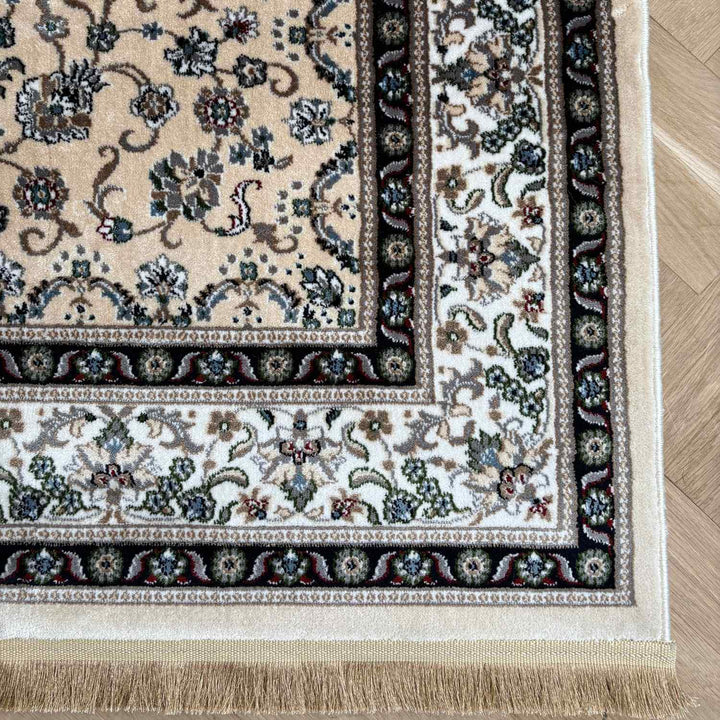 Corner of a patterned rug with intricate designs on a wooden floor.