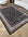 Decorative black and white patterned rug on a wooden floor with a sofa and chair in the background.