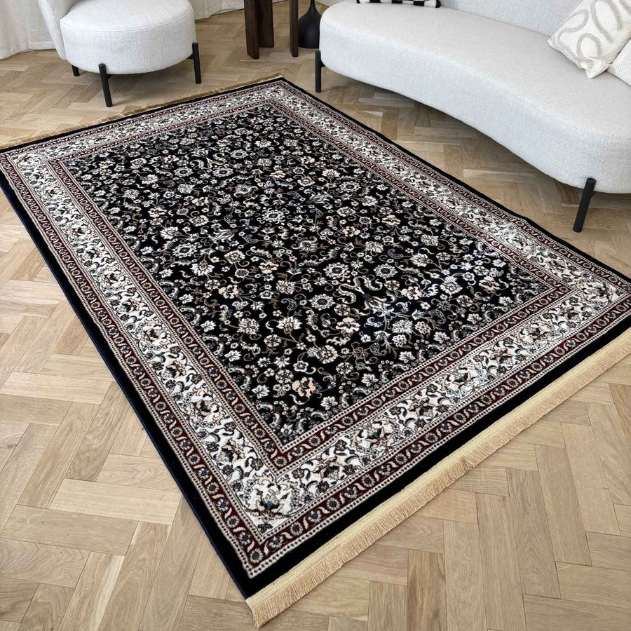 Decorative black and white patterned rug on a wooden floor with a sofa and chair in the background.
