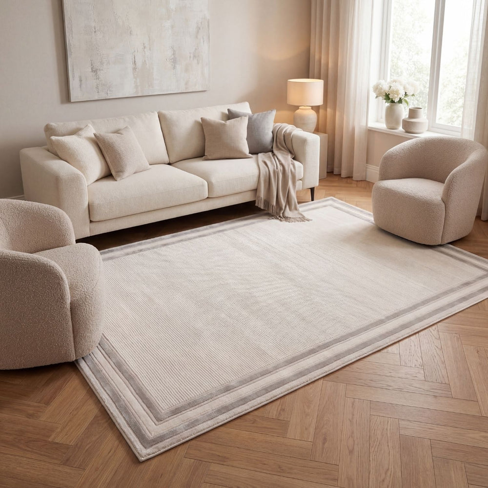 Living room with a beige sofa, armchair, and rug on a wooden floor.
