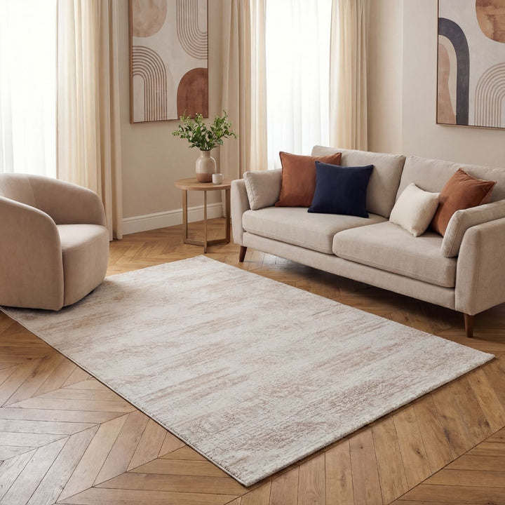 Living room with beige sofa, armchair, and rug on wooden floor.
