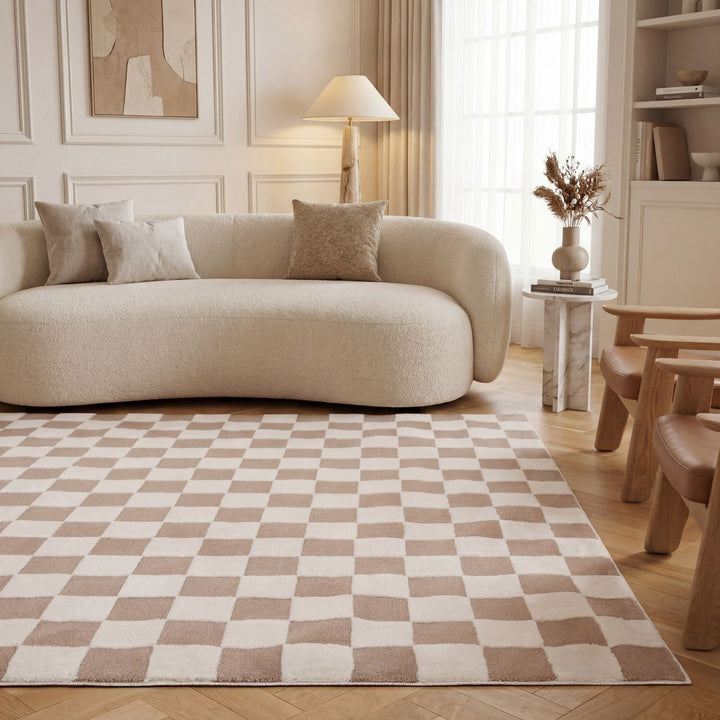 Beige sofa in a living room with a checkered rug and wooden furniture.