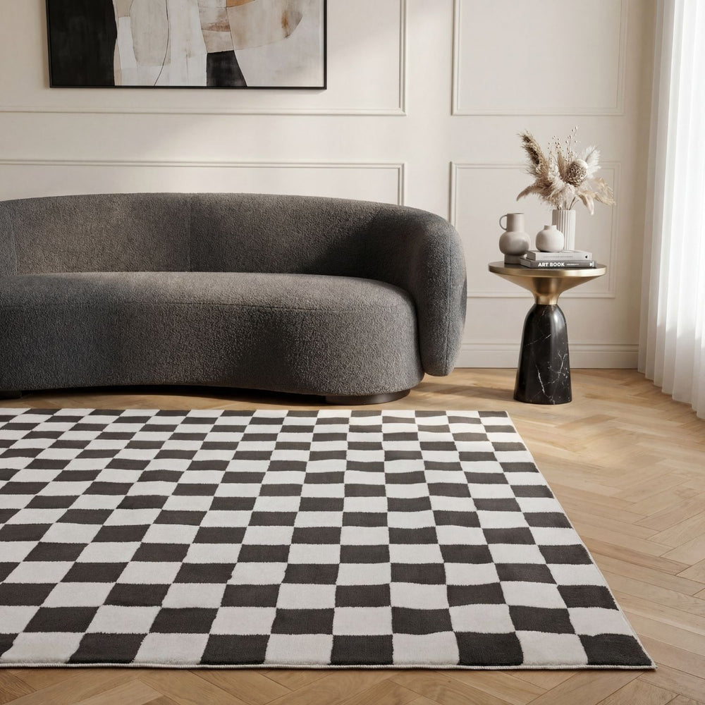 Modern living room with a checkered rug, gray sofa, and side table.