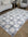 Checkered area rug on a wooden floor with a sofa and chair in the background.