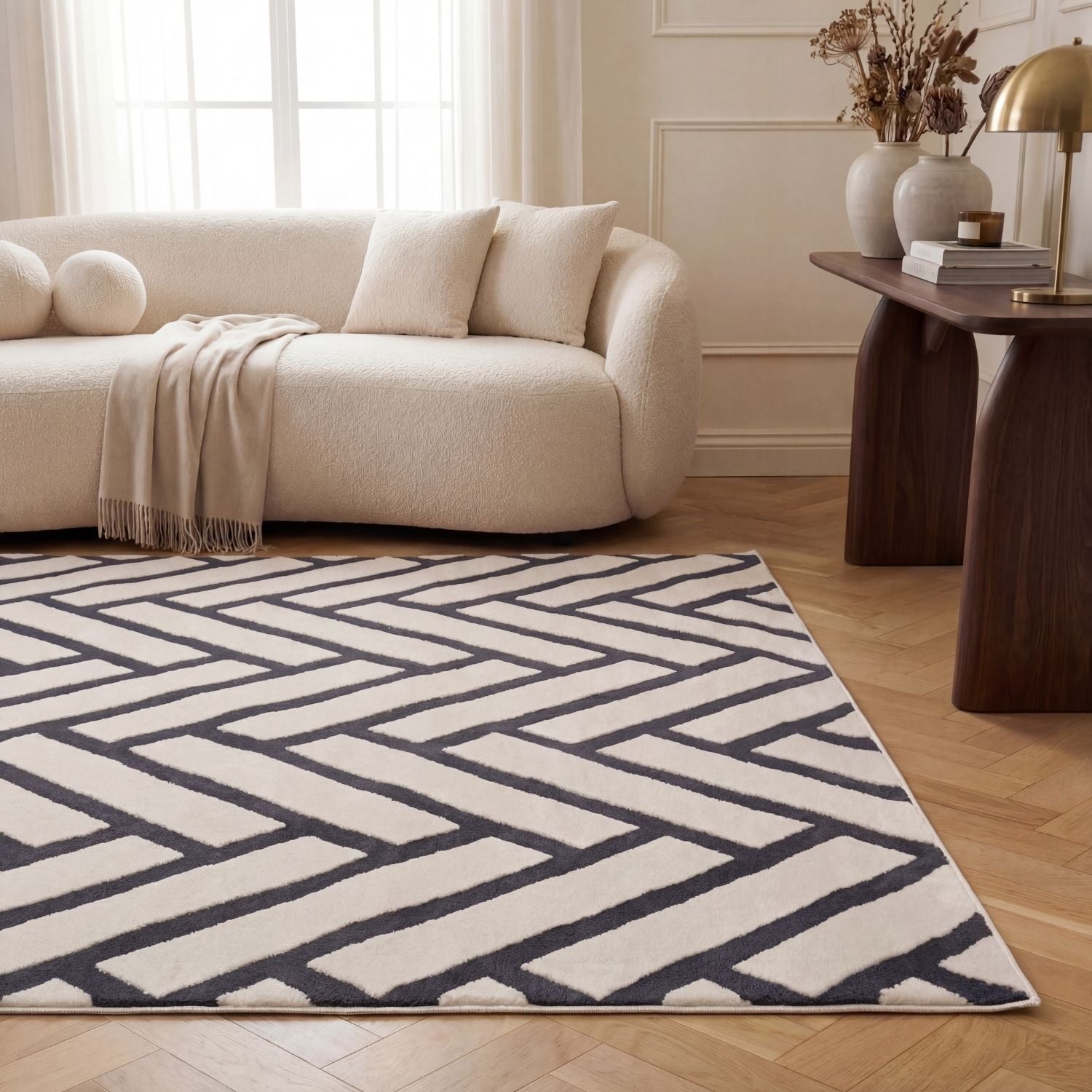 Living room with a geometric patterned rug, beige sofa, and wooden side table.