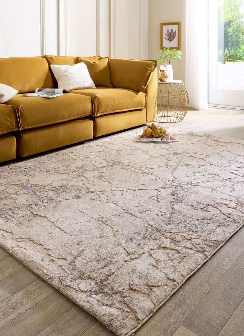 Abstract geometric rug in neutral tones of beige and grey, placed in a cozy living room with a yellow sofa.