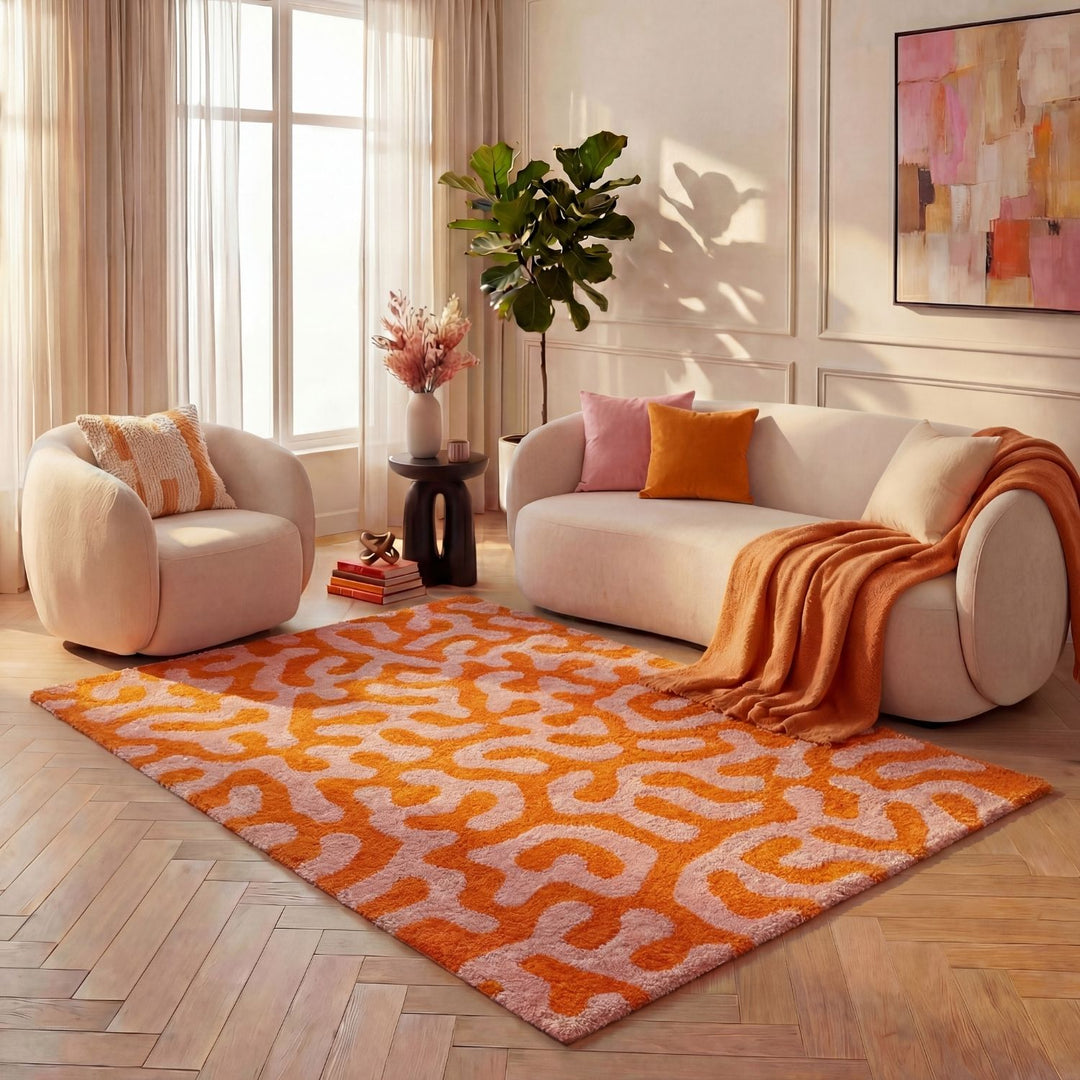 Orange and pink patterned rug on a wooden floor with a sofa and chair in the background.