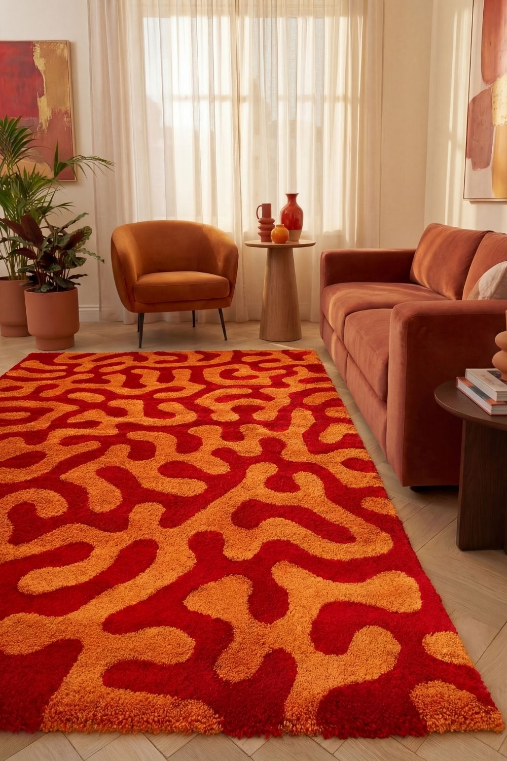 Living room with a red and orange patterned rug, brown sofa, and armchair.