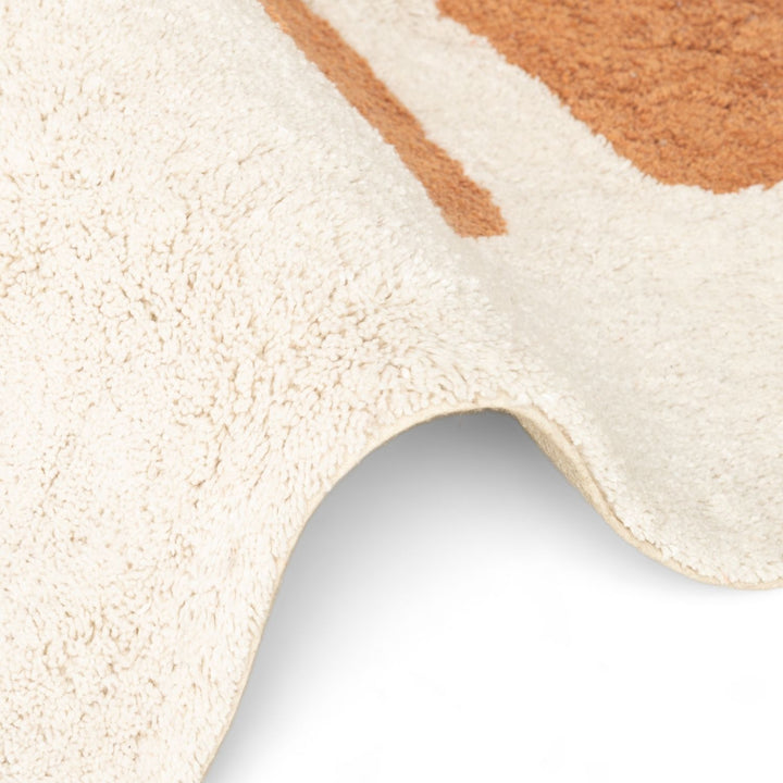 Close-up of a textured beige and brown rug corner on a white background