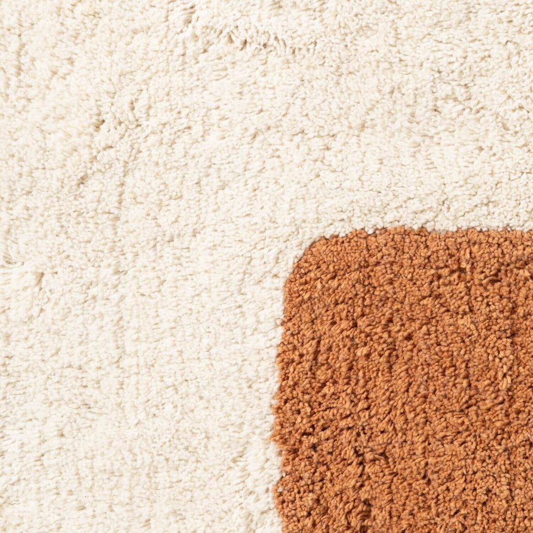 Close-up of a beige carpet with a brown doormat corner.