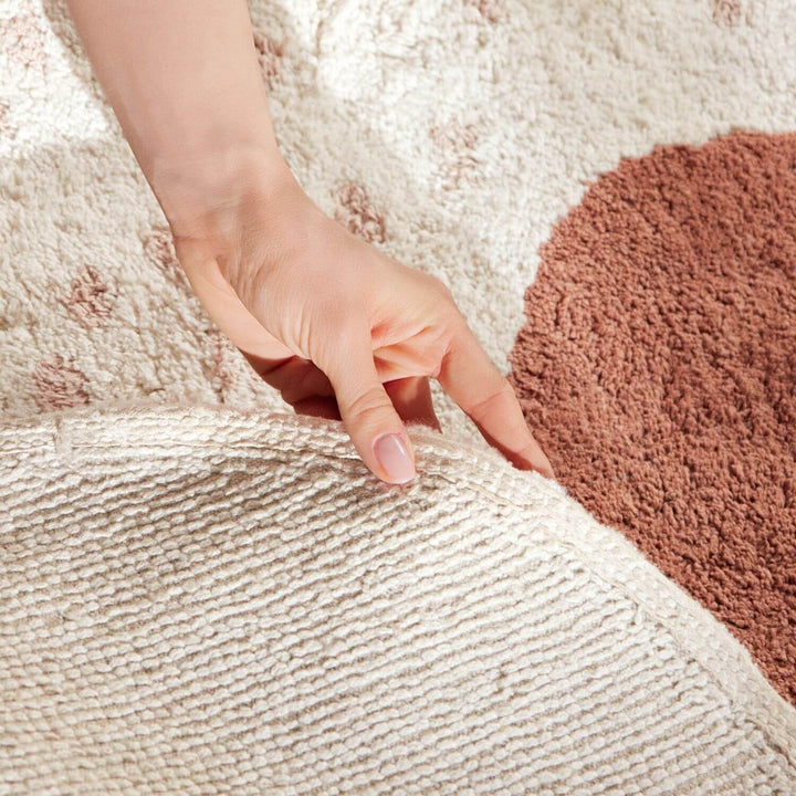 Hand touching a textured beige and brown rug