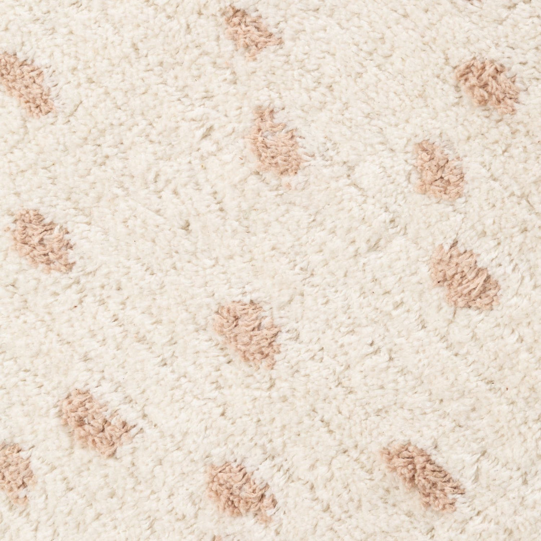 Close-up of a textured beige carpet with small brown patches