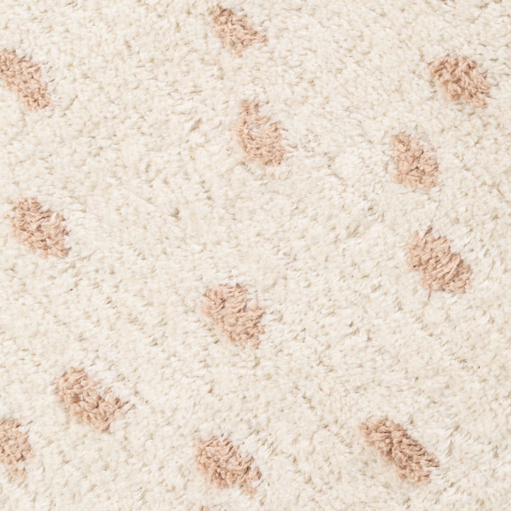 Close-up of a textured beige carpet with small brown patches