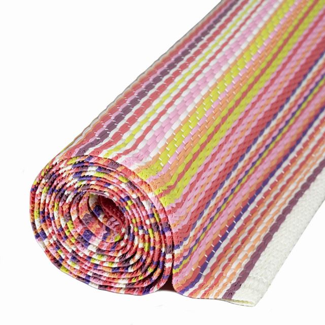 Rolled pink rainbow outdoor rug with colorful striped geometric patterns, ideal for vibrant outdoor decor.