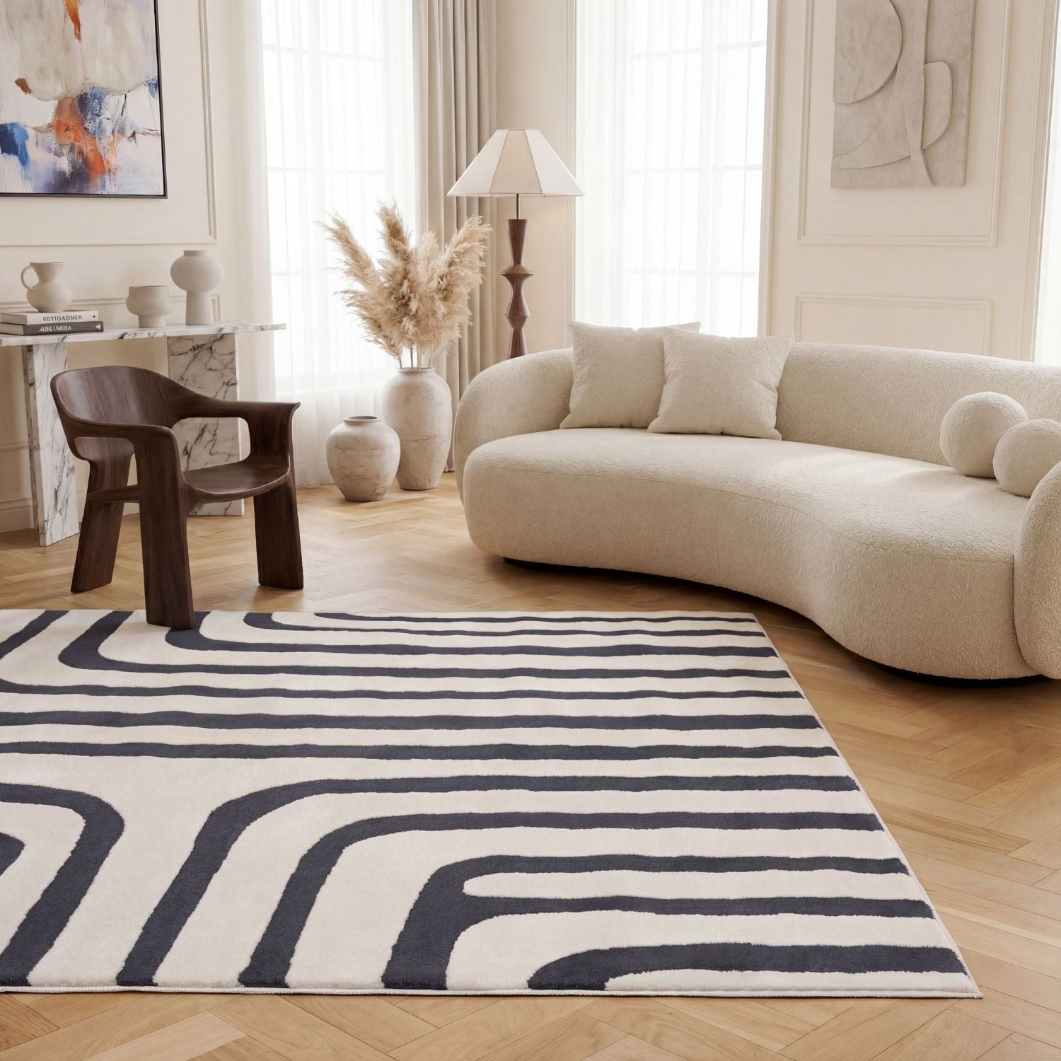 Modern living room with a curved beige sofa, wooden chair, and a patterned rug.