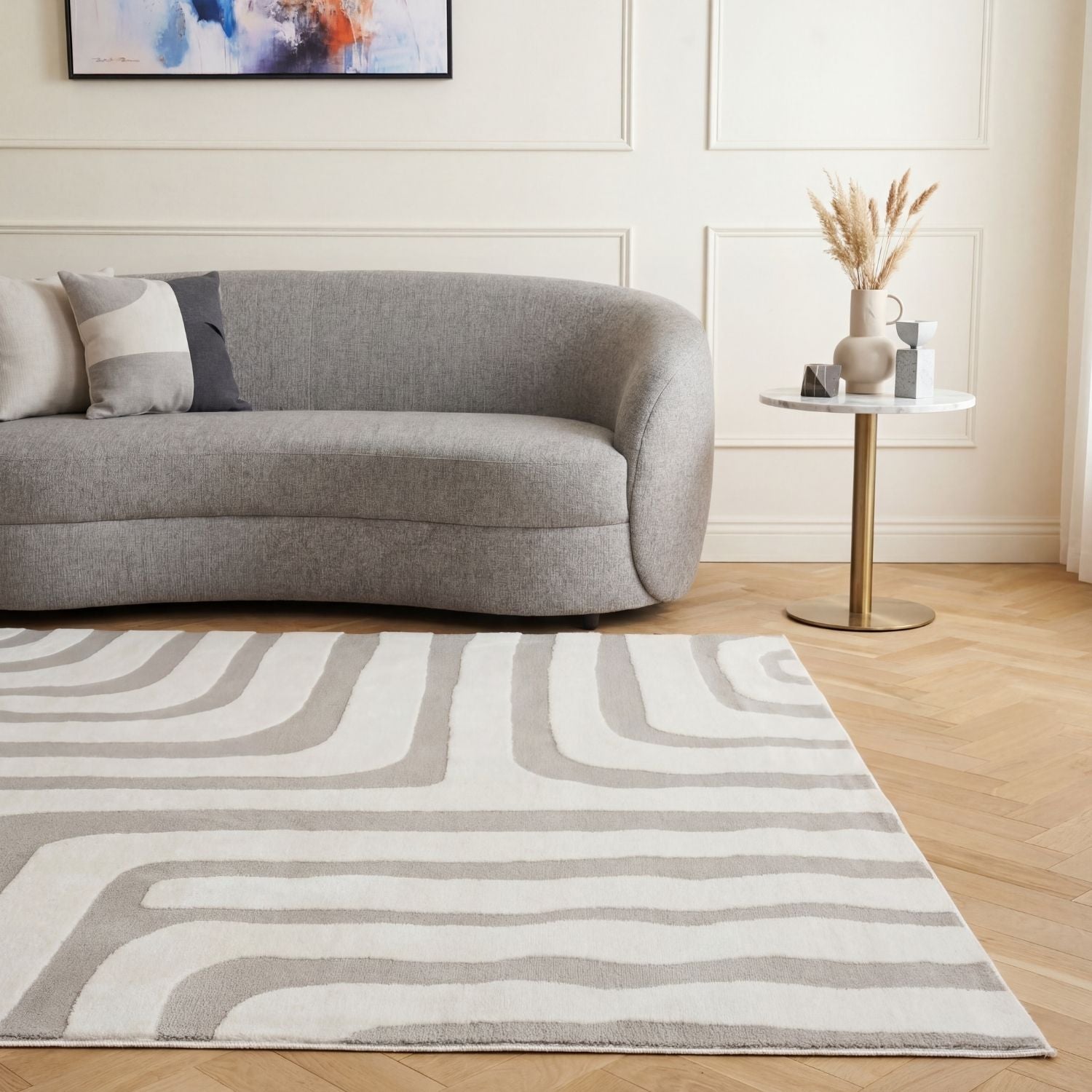 Living room with a gray sofa, abstract painting, and patterned rug.