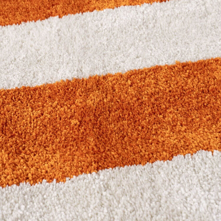 Close-up of a striped rug with orange and white stripes.