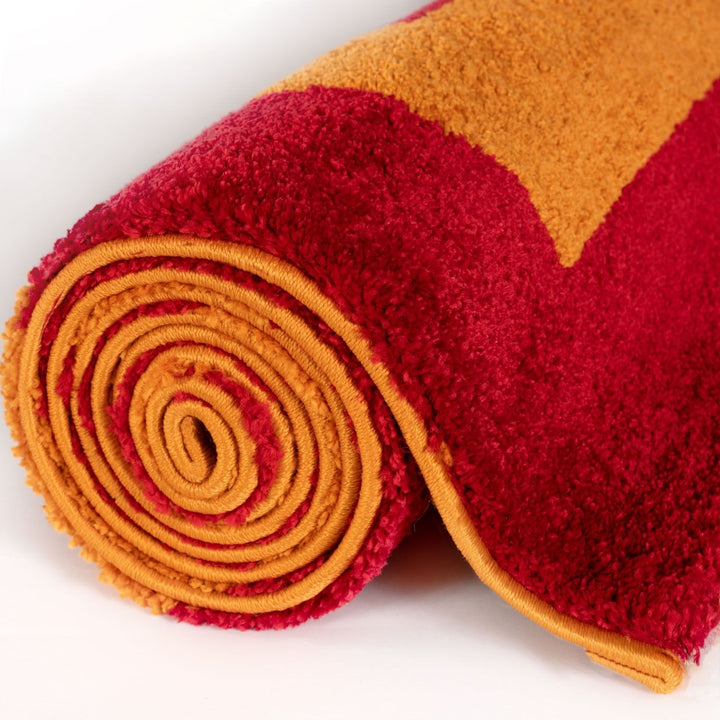 Roll of red and orange textured fabric on a white background