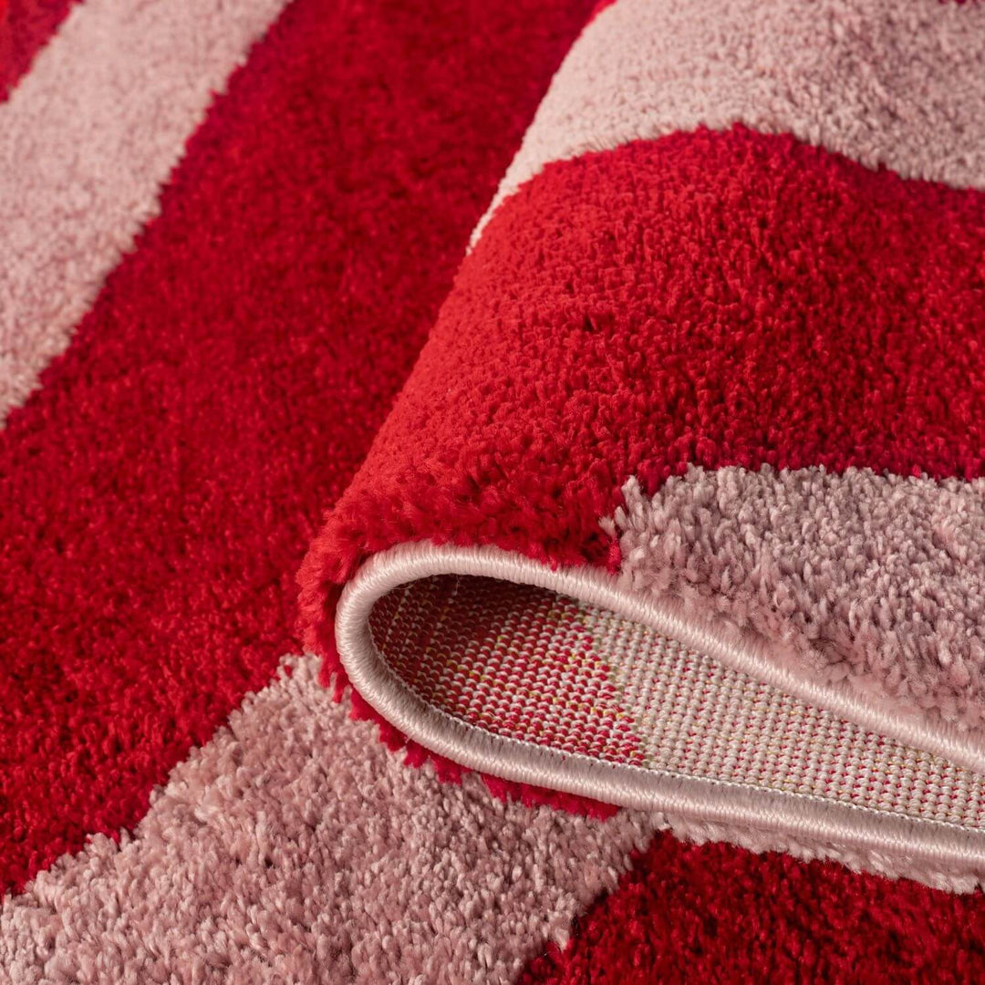 Close-up of a red and pink striped rug with a textured border.