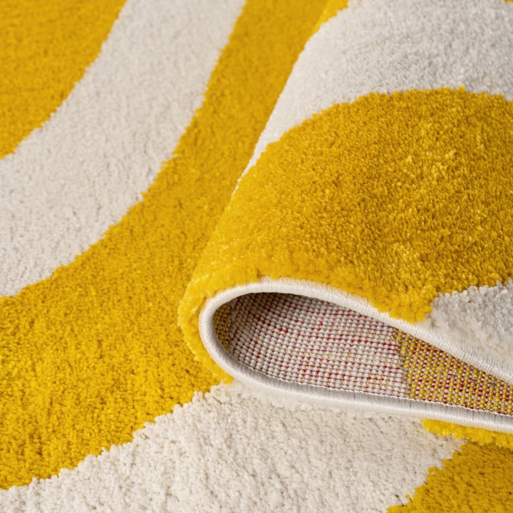 Close-up of a yellow and white patterned rug with a shoe partially on it.