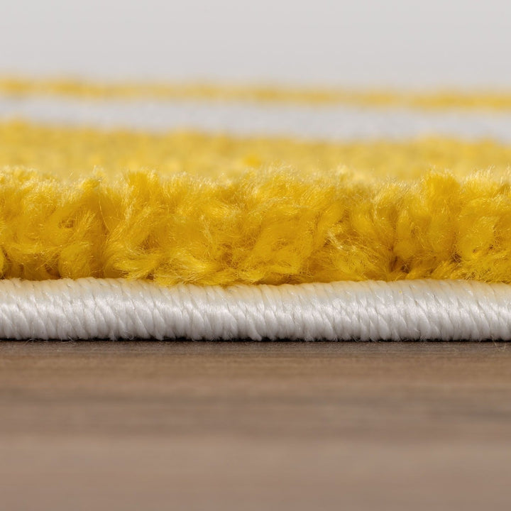 Close-up of a yellow and white carpet border on a wooden floor.