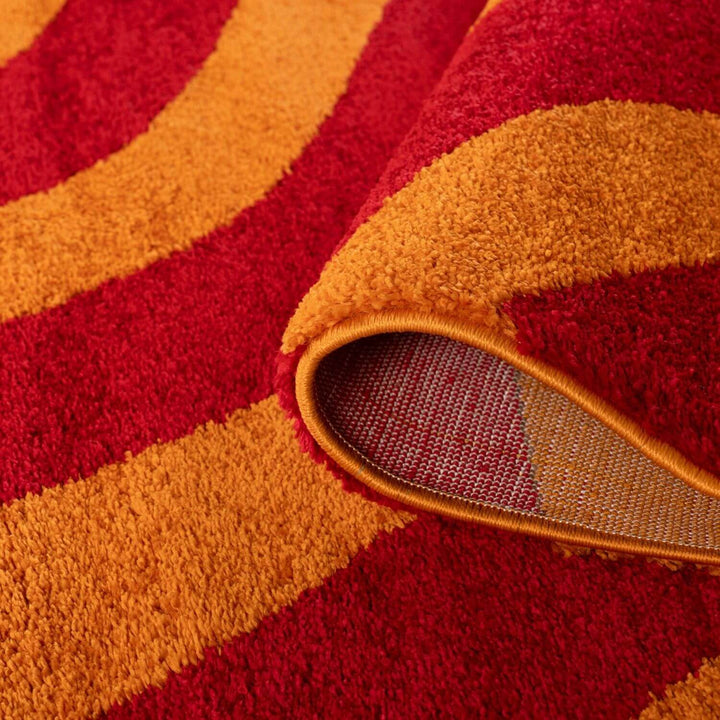 Close-up of a red and orange patterned rug with a visible edge.