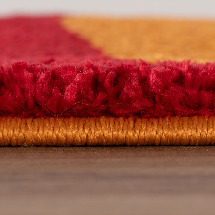Close-up of a red and orange textured rug on a wooden floor.