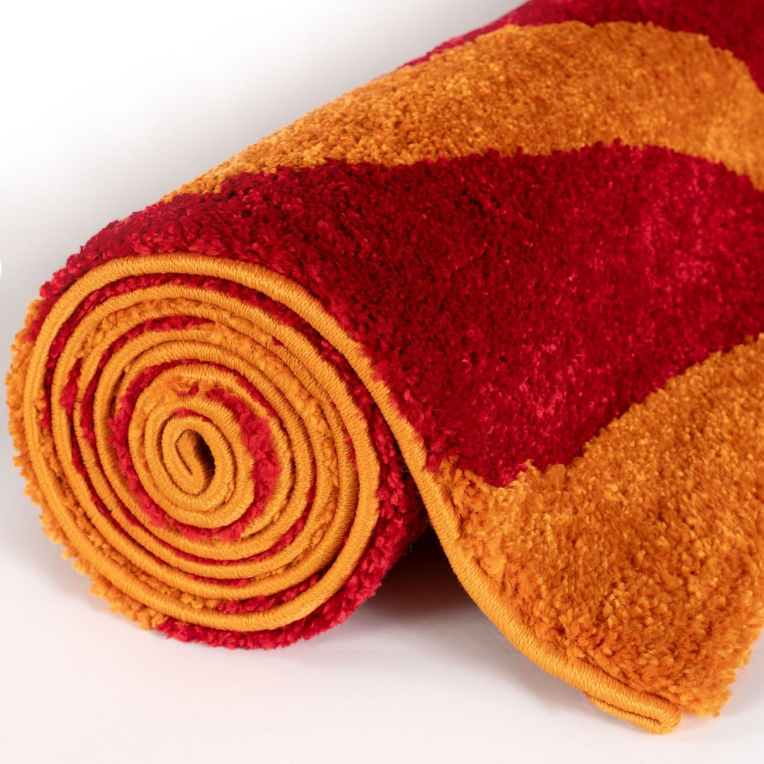 Roll of red and orange textured fabric on a white background