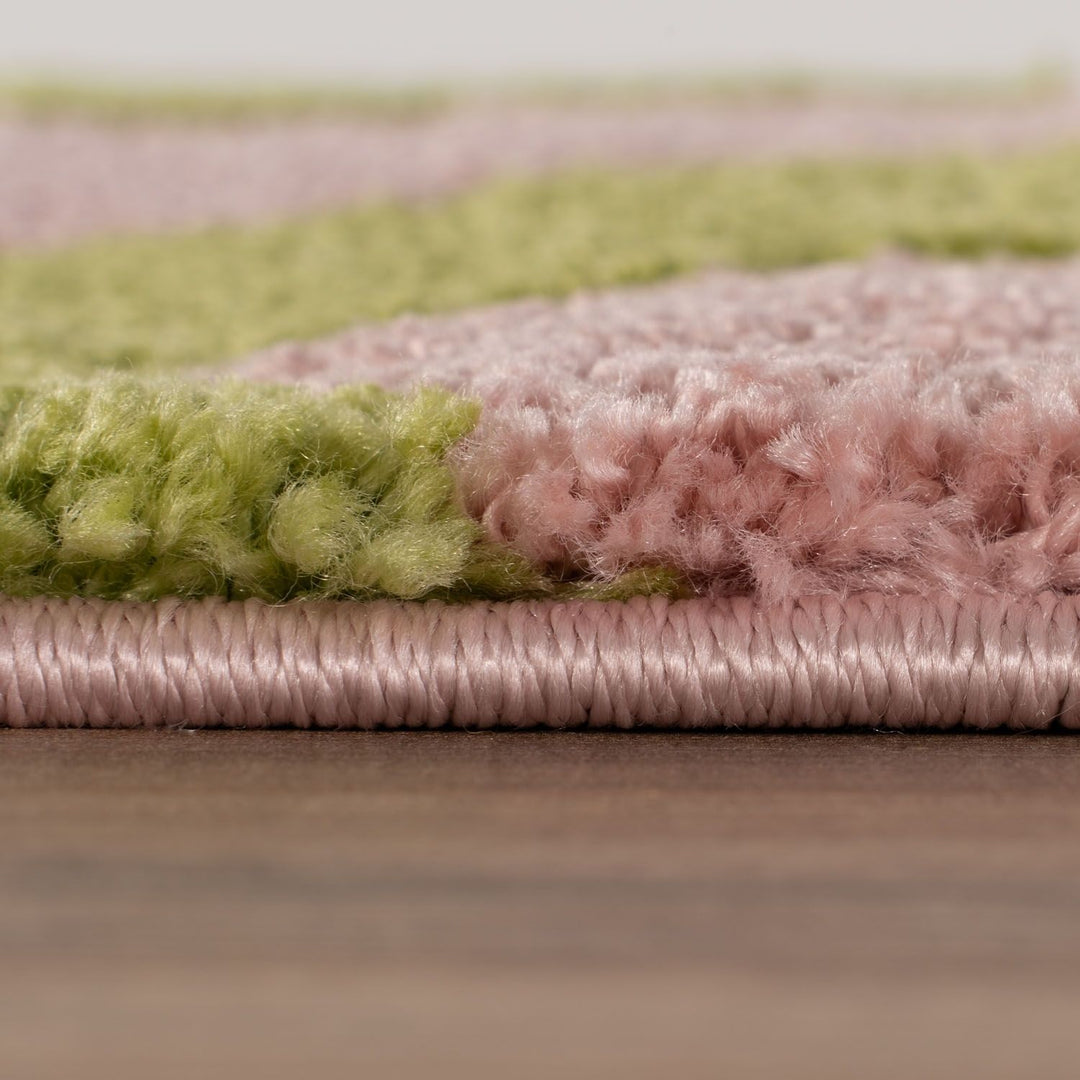 Close-up of a pink and green textured rug on a wooden floor.