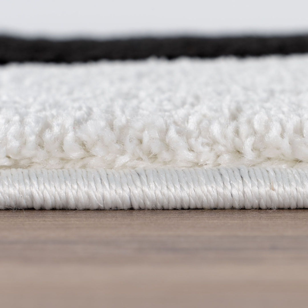 Close-up of a white rug with a textured surface on a wooden floor.