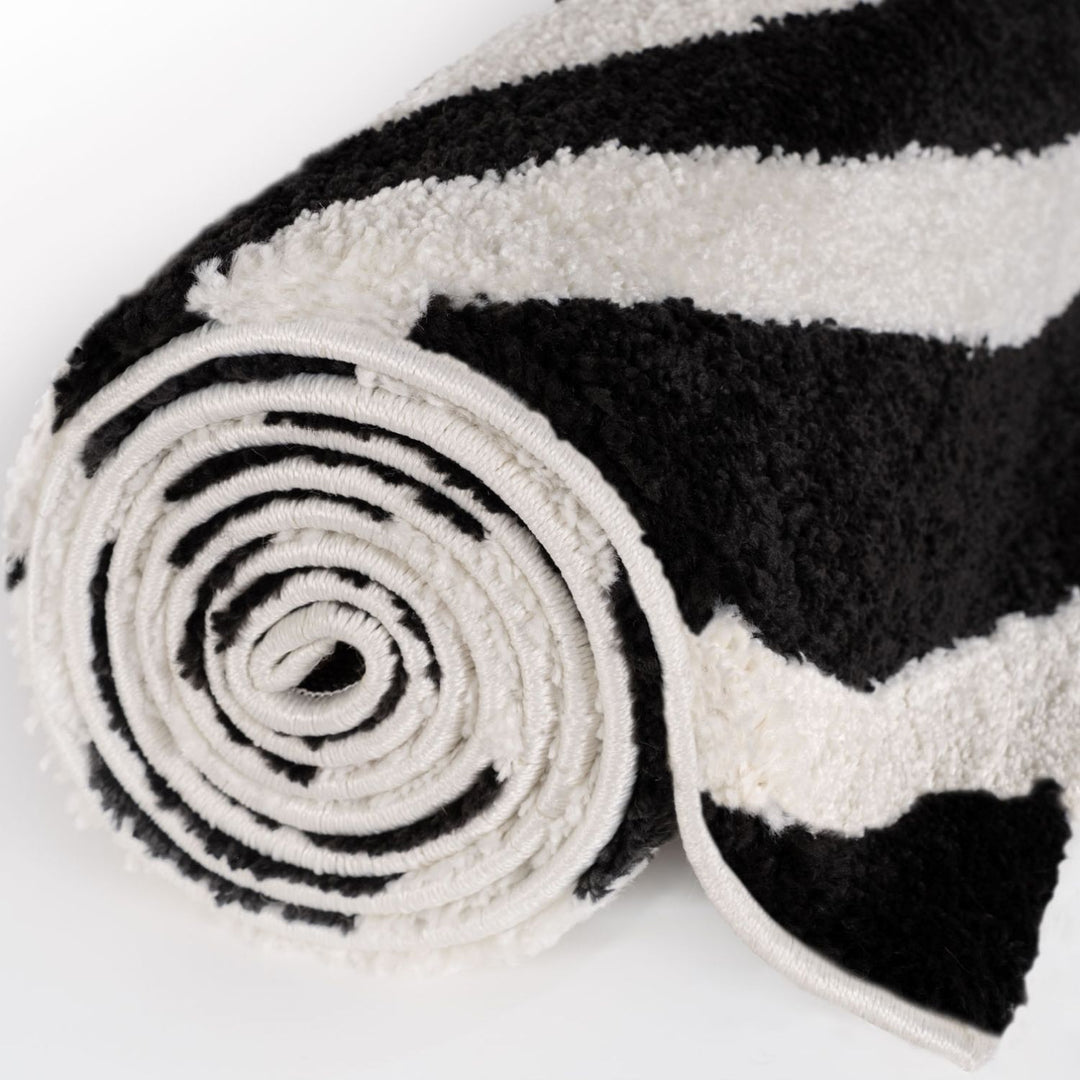 Black and white striped rug rolled up on a white background