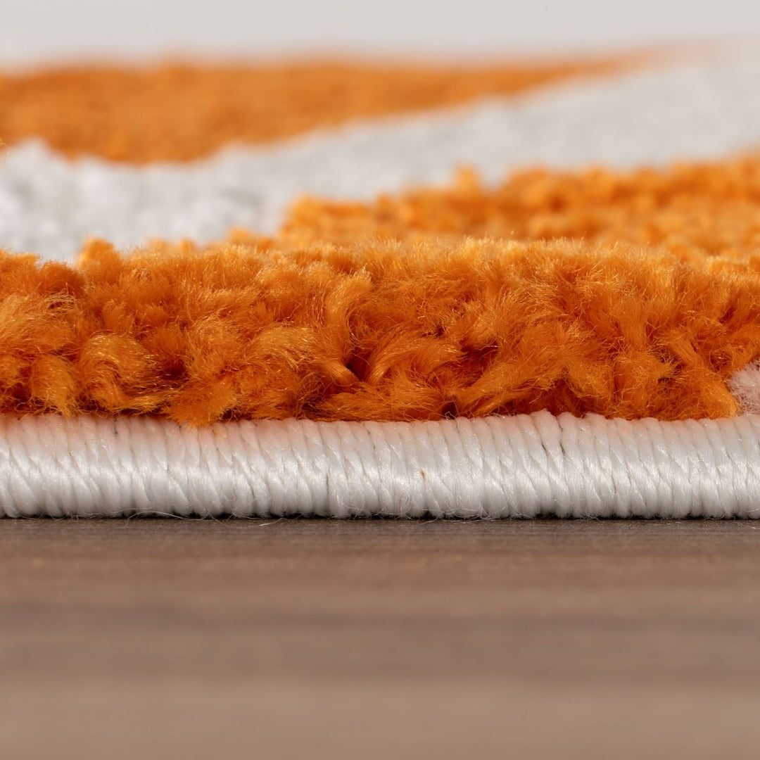 Close-up of an orange and white striped rug on a wooden floor.
