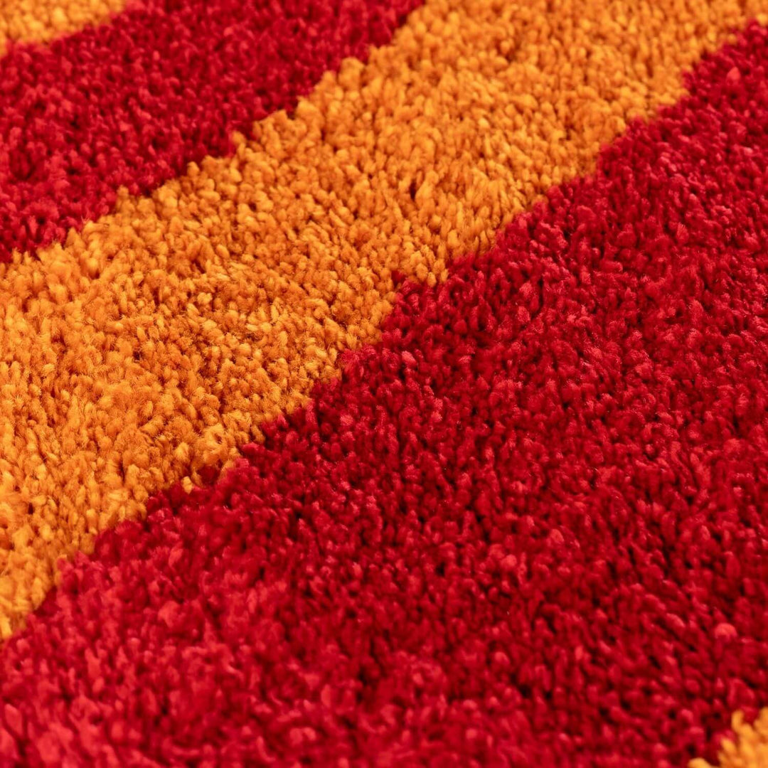 Close-up of a textured red and orange rug with a wavy pattern.