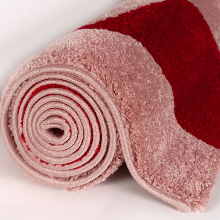 Two rolled-up towels, one pink and one red, on a white background