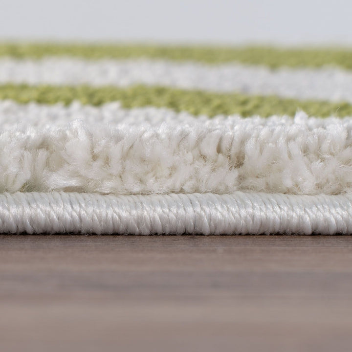 Close-up of a white and green striped rug on a wooden floor.