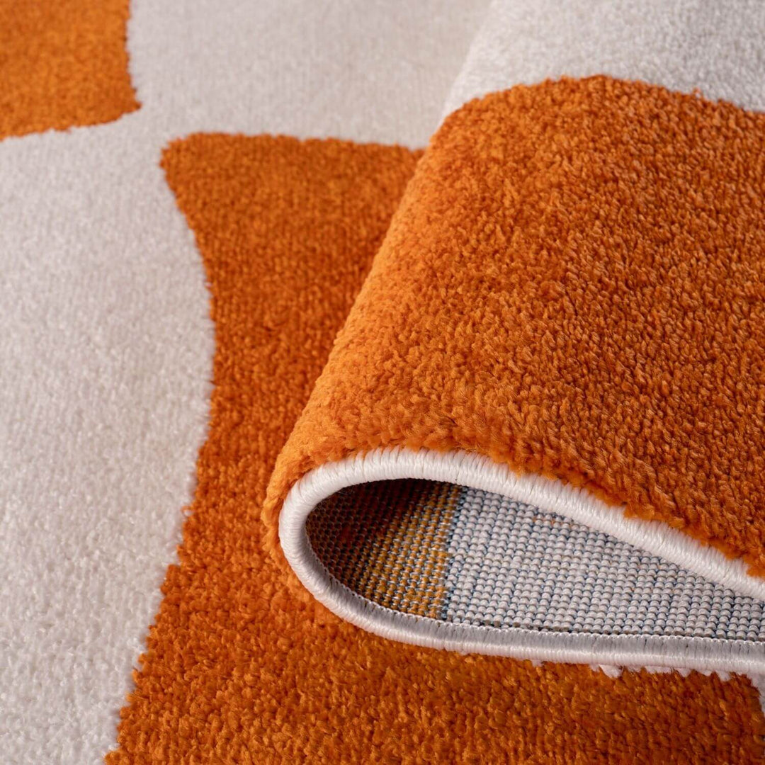 Close-up of an orange textured rug with a white border on a neutral background