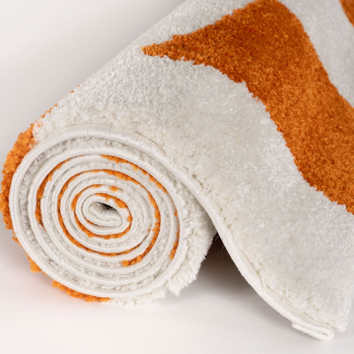 Rolled-up towel with white and orange pattern on a light background