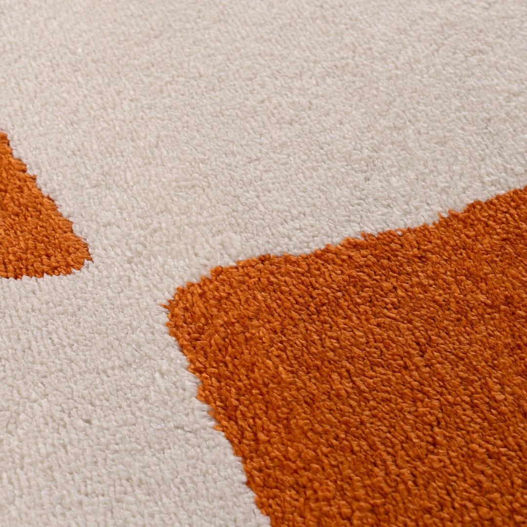 Close-up of a textured rug with orange and beige colors